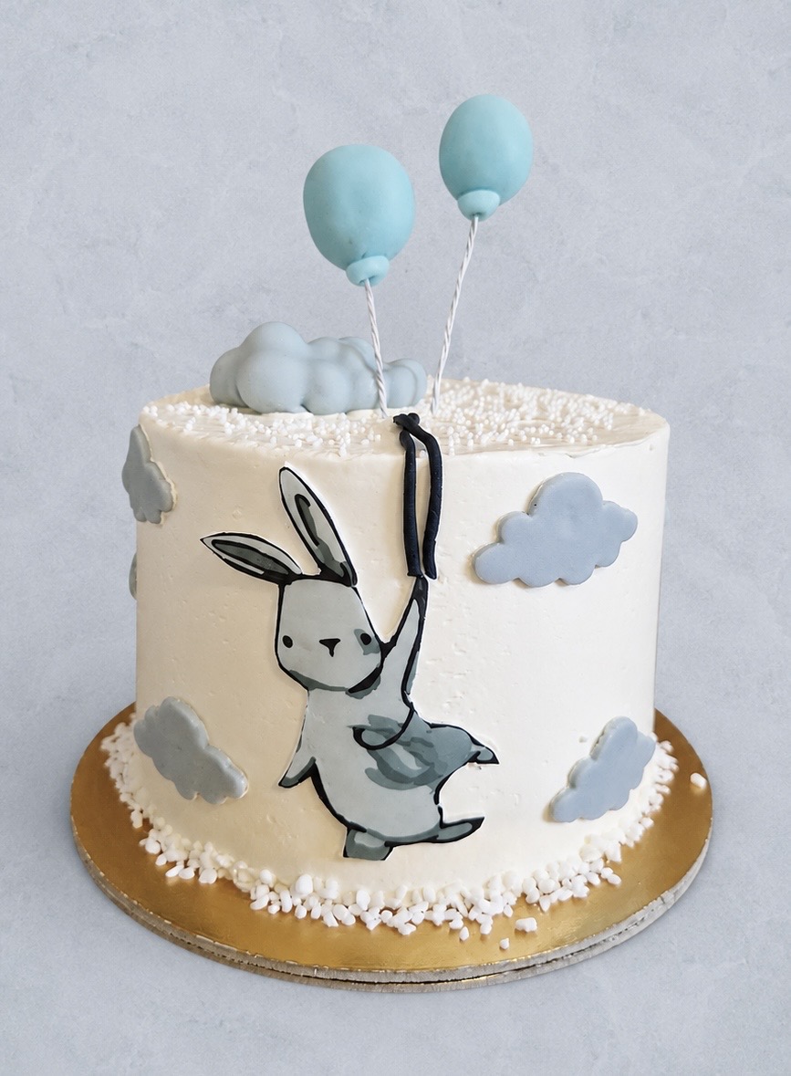 Fehér vajkrémes torta festett nyuszival és kék lufikkal