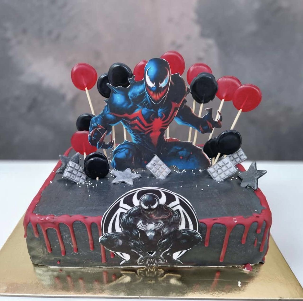 Fekete Venom témájú torta piros csorgatással és nyalókákkal