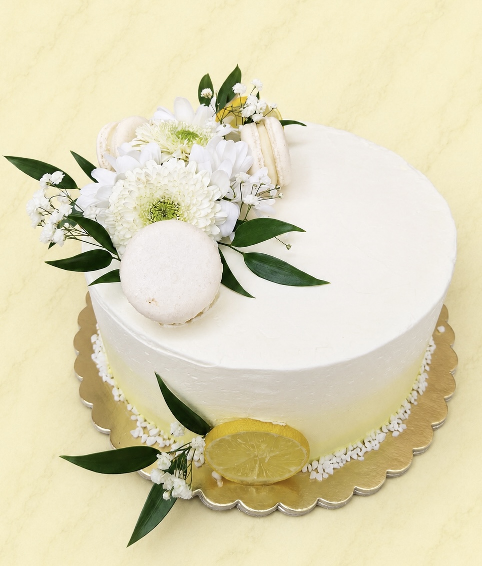 Fehér torta élővirágokkal, macaronokkal és citrommal